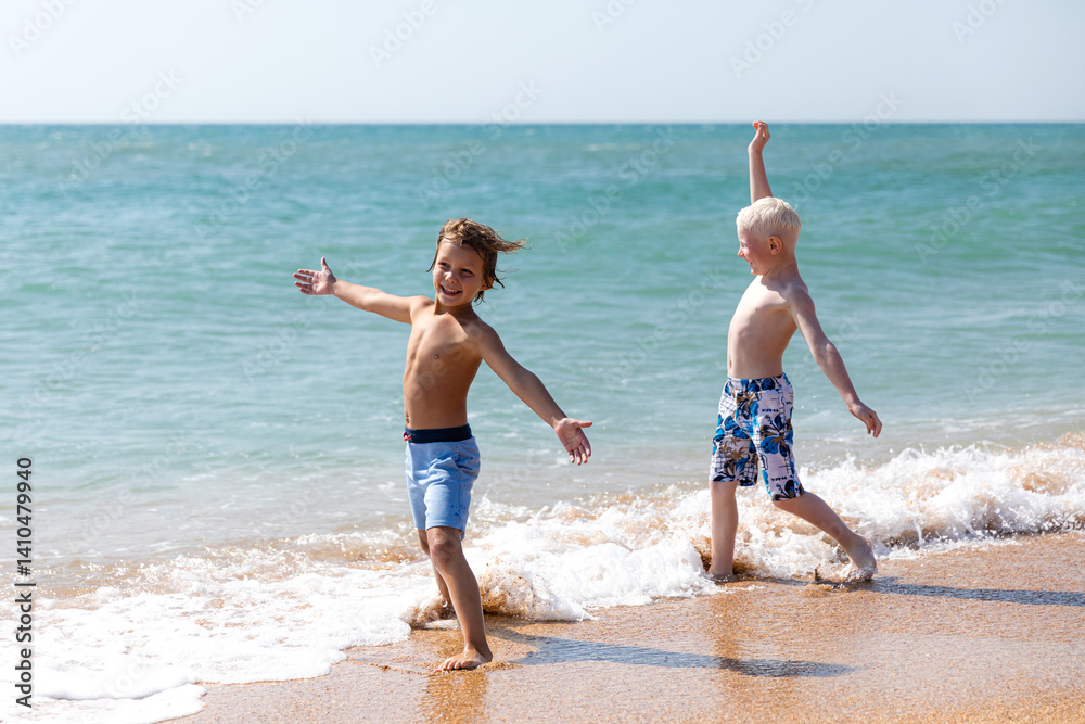 Happy children, two little boys, enjoy summer vacation near the sea, play on sandy beach, have fun. Advertising for tour operators, hotels, airlines. Childhood, happiness and freedom concept.