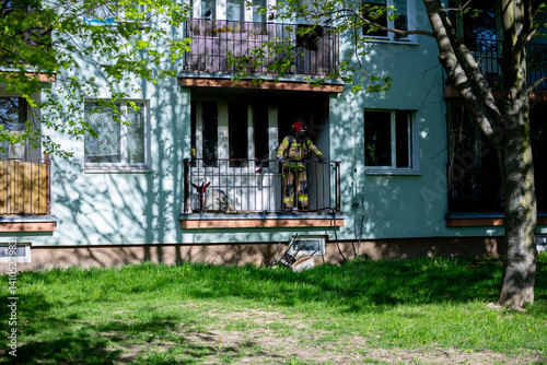 A soldier stands on a balcony, observing the vibrant urban environment all around him