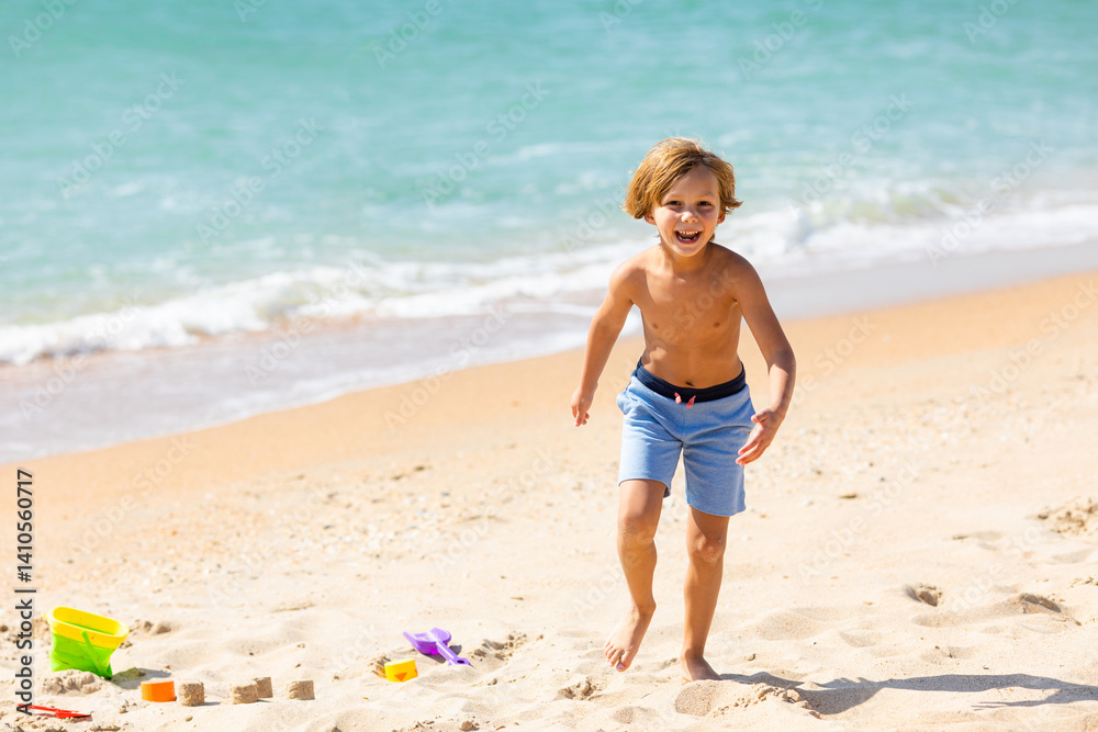 Happy child little boy playing on the beach, building sand castle, enjoying summer, playing. Advertising for tour operators, hotels, airlines. Vacation concept.