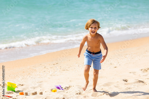 Happy child little boy playing on the beach, building sand castle, enjoying summer, playing. Advertising for tour operators, hotels, airlines. Vacation concept.