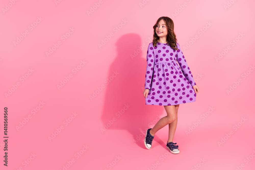 Smiling cute girl in a trendy purple dotted dress posing against a bright pink background showcasing childhood fashion and joy. Smiling cute girl in a trendy purple dotted dress posing against a bright pink background showcasing childhood fashion and joy.
