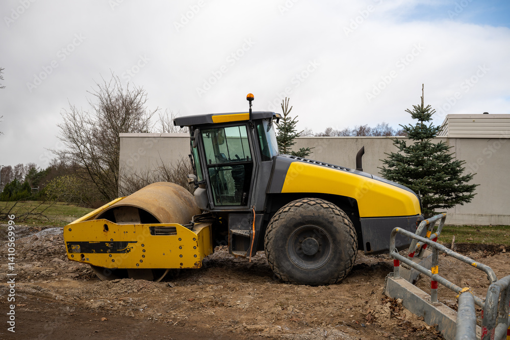 Yellow road roller parked on construction site Yellow road roller parked on construction site