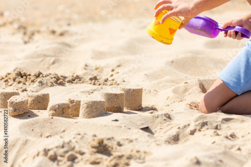 Obraz na płótnie Close up hands of little boy playing with the sand on the beach, building sand castle, enjoying summer, playing. Advertising for tour operators, hotels, airlines. Vacation concept. w salonie