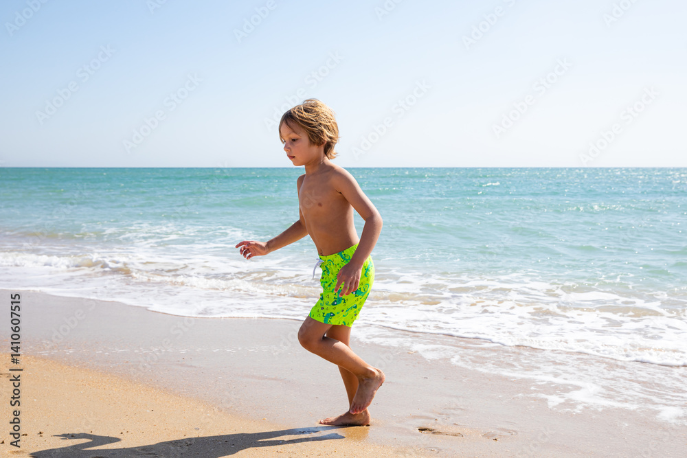 Cute little boy playing on the beach on summer vacation. Joyful child in nature with beautiful sea and sand background. Happy kid on vacation, walking on the beach and having fun. Freedom concept