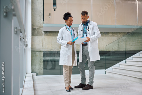 Healthcare workers analyzing medical reports in a hallway of at the clinic.