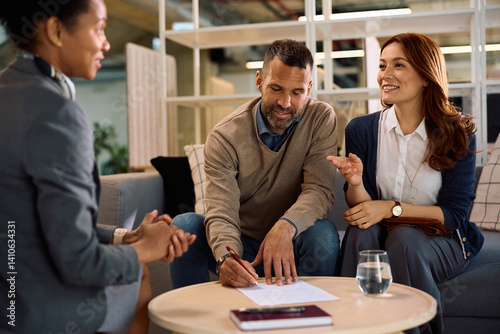 Tableau sur toile Happy couple signing a contract with their insurance agent in the office