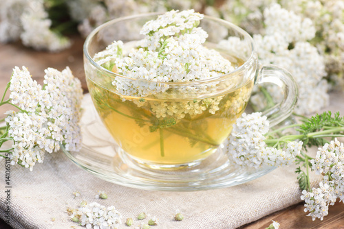 Yarrow flower tea in glass cup with plant, naturopathy and natural medicine concept