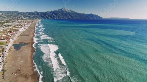 Turquoise waves rolling and crashing near mount killini, drepanos beach creating serene coastal landscape under clear blue greek sky