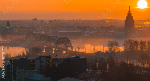 Obraz na płótnie A warm sunrise illuminates Riga, Latvia, with the arched railway bridge over the Daugava River and the Latvian Academy of Sciences in the background. w salonie