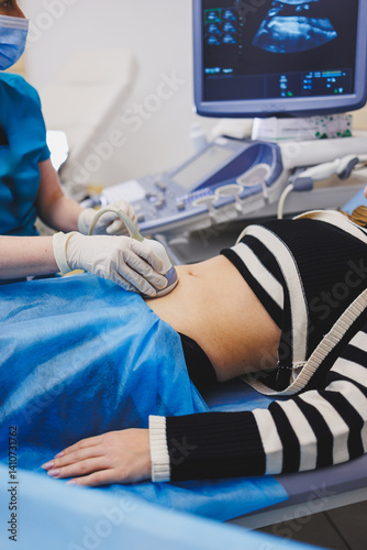 Obraz na płótnie Ultrasound examination of the abdomen of a pregnant woman. Close-up of the abdomen of a pregnant woman. Checking the condition of the fetus using a sensor through the abdomen. w salonie