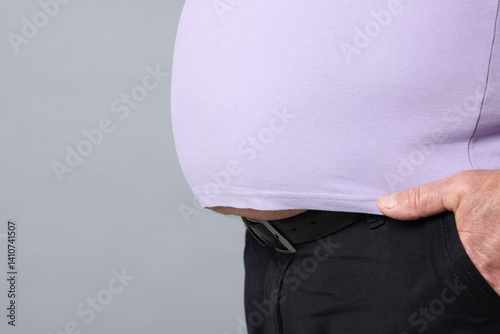 Overweight man in tight t-shirt on grey background, closeup. Space for text
