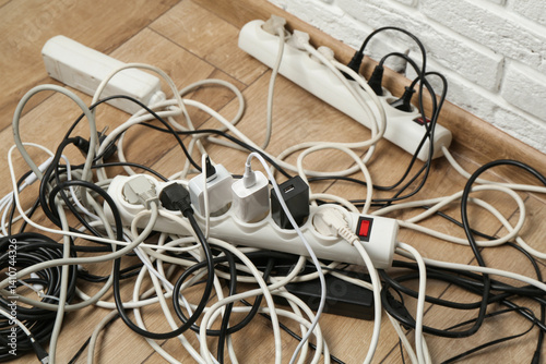 Konstfotografi Extension power boards overloaded with plugs on wooden floor, closeup