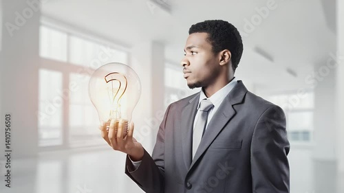 A man in a suit holds a glowing light bulb with a question mark, symbolizing ideas and innovation.