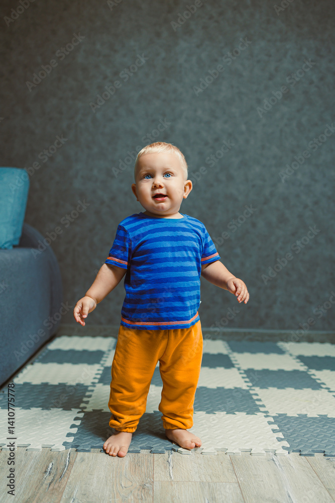Toddler boy in a T-shirt and pants playing with toys at home. Children's home clothes. Child's self-development at home.