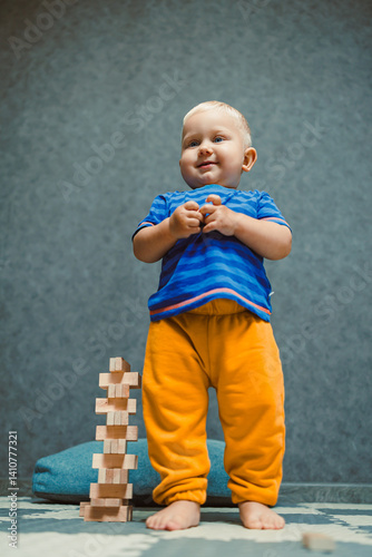 Obraz na płótnie A one-year-old boy at home in a t-shirt and pants is playing in the room. The child is having fun playing on his own. w salonie
