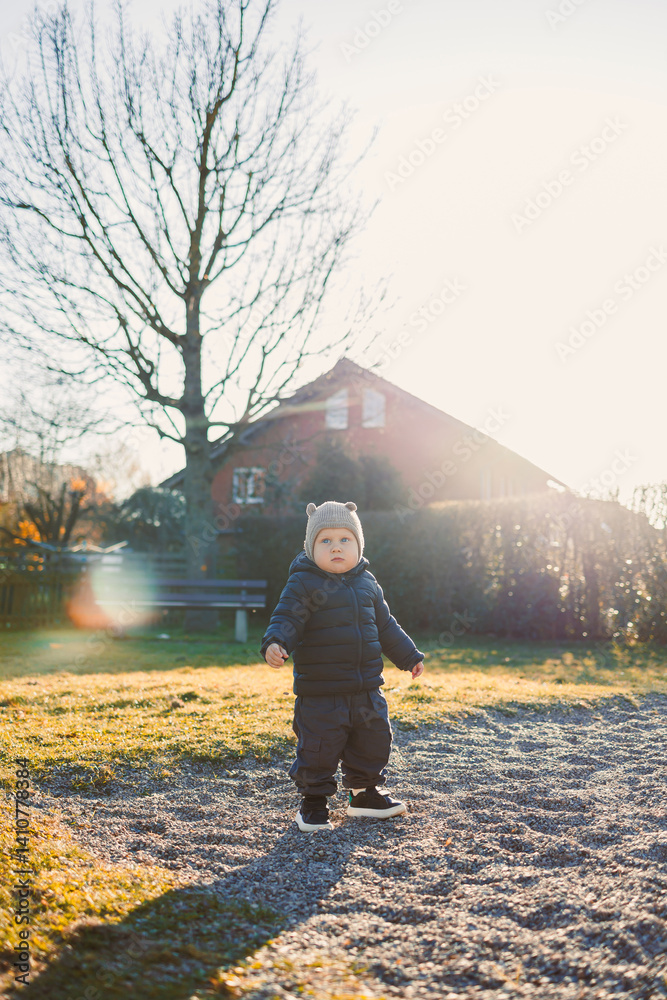 Little boy in a jacket and hat on a spring walk on the playground. Child's walk outdoors. children's stylish spring clothes