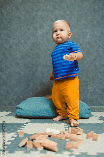 Toddler boy in a T-shirt and pants playing with toys at home. Children's home clothes. Child's self-development at home.