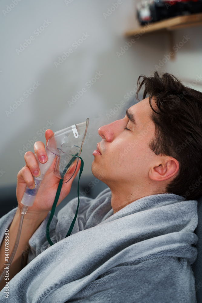 Sick man has respiratory treatment by nebulizer. Inhaling air by nebulizer mask for cough therapy at home. Sick man has respiratory treatment by nebulizer. Inhaling air by nebulizer mask for cough therapy at home.