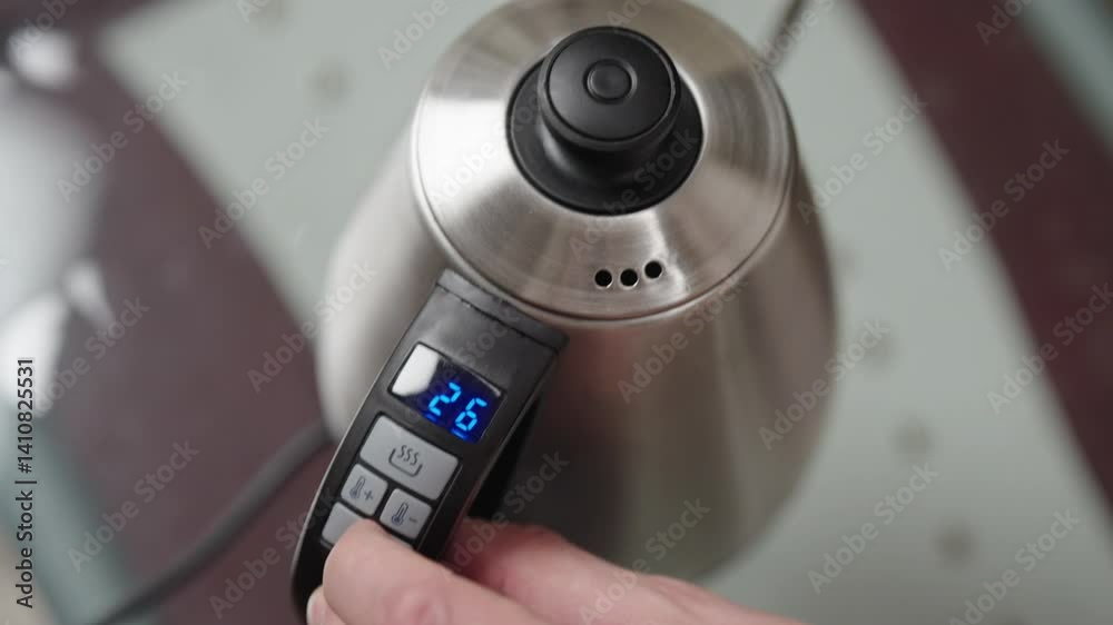 Man setting temperature and timer on electric kettle and closing lid, preparing for steaming hot beverage in kitchen, close-up. Concept of morning routine with convenience. Shooting in slow motion. Man setting temperature and timer on electric kettle and closing lid, preparing for steaming hot beverage in kitchen, close-up. Concept of morning routine with convenience. Shooting in slow motion.