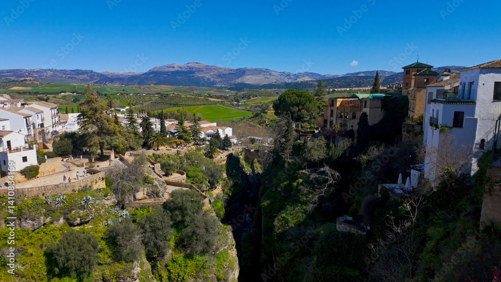 Fototapeta premium Ronda, Spain showcasing Puente Nuevo bridge, gorge, and white houses under blue sky