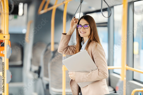 Obraz na płótnie Portrait of fashionable young lady with laptop riding public city bus. w salonie