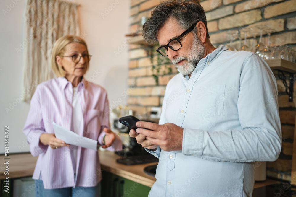 Obraz premium mature couple review, analysis document and use mobile at kitchen