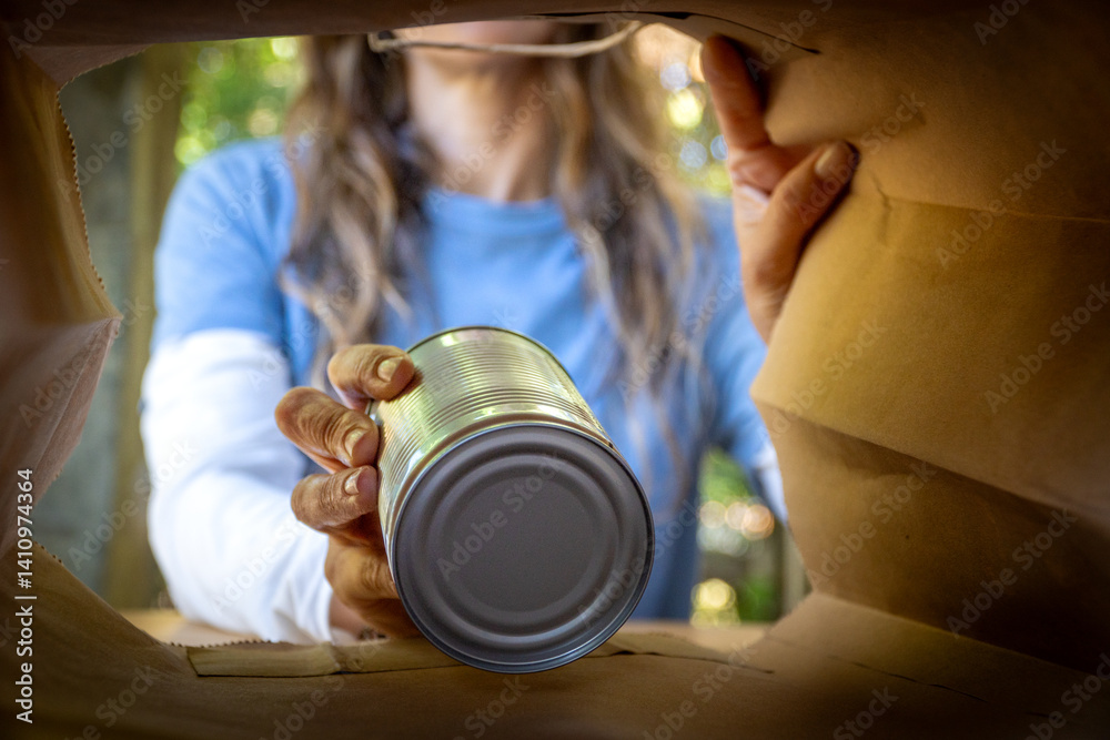 Female Volunteer Packing Canned Food into a Paper Bag