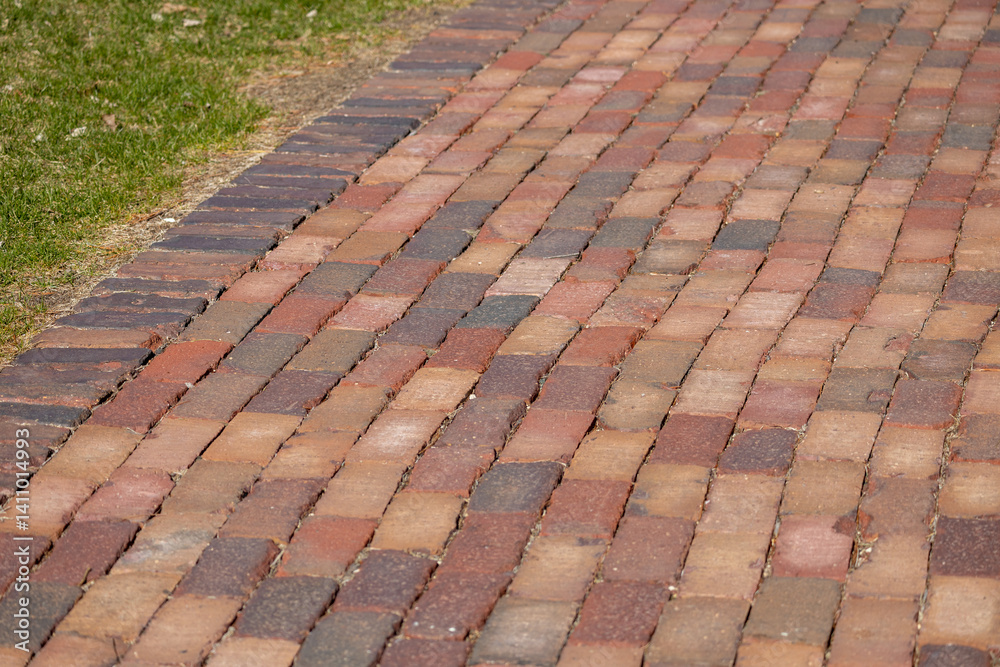 Fototapeta premium Full frame texture background of a colorful vintage red hued brick cobblestone pedestrian walkway in dappled sunlight