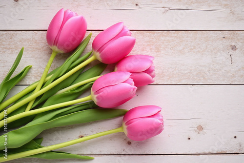 bunch of pink tulips on a wooden table