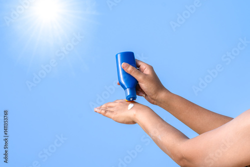 Hand of female holding sunscreen. Very sun light Sky background.Health concepts and skin care