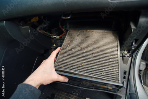 Obraz na płótnie Closeup of person removing dirty cabin air filter from car during regular maintenance showing dust buildup and the importance of clean air in vehicle interiors. Selective focus w salonie
