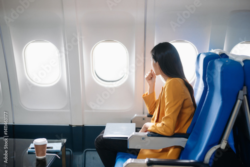 Photo of a frustrated woman sitting on an airplane with her head in her hands. Asian woman sitting