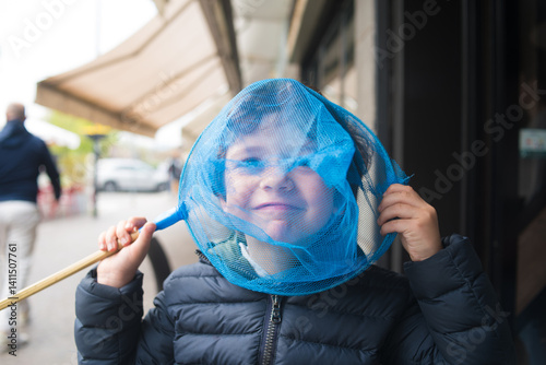 Young boy plays with a net in a busy street