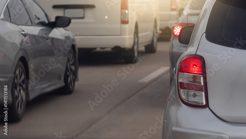 Rear side of Silver Bronze car with turn on brake light. Many cars driving on the road for business trip or travel. Everonment in the city.