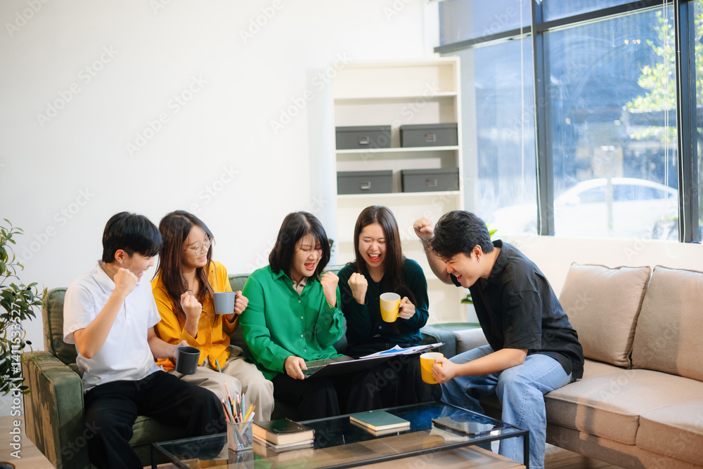 Obraz premium Group of young adults in casual wear, using laptops and headphones, enjoying teamwork,