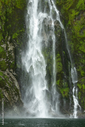 Raging waterfall and greenery of Mildford Sound, New Zealand