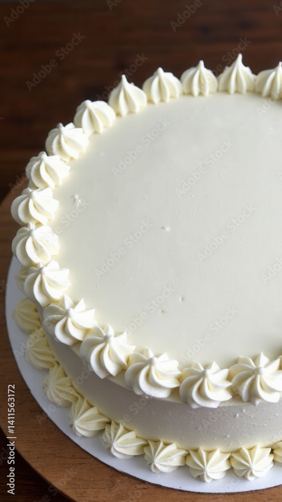 Large white cake with a blank top on a wooden table.