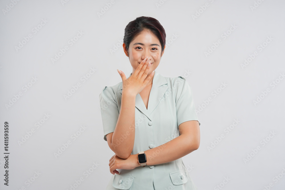 Young woman smiles shyly covering her mouth with her hand wearing a light green blouse Young woman smiles shyly covering her mouth with her hand wearing a light green blouse