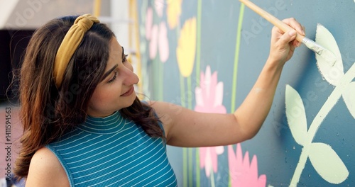 Woman, smile and painting in city for mural art, creative wall and social responsibility to uplift community. Volunteer, creativity and outdoor with project for floral design, public service and DIY