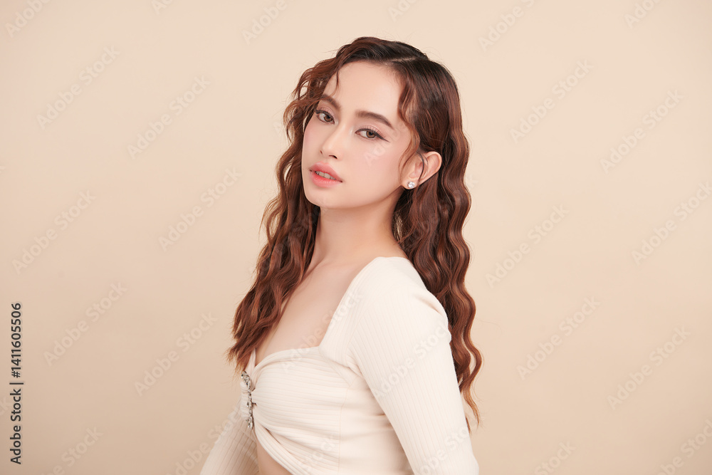 Fototapeta premium A beautiful young Asian woman with clean, fresh skin against a beige background. Skincare, facial treatment, cosmetology, beauty, and spa. An elegant portrait of an Asian woman.