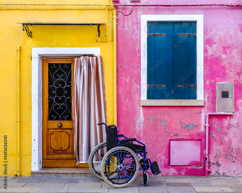 Colorful doorway with a wheelchair outside a vibrant pink and yellow building in a scenic urban setting during daytime