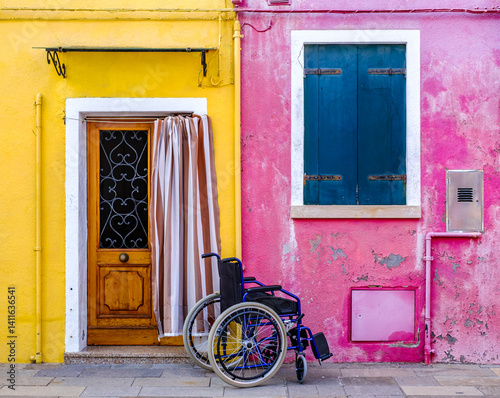 Obraz na płótnie Colorful doorway with a wheelchair outside a vibrant pink and yellow building in a scenic urban setting during daytime w salonie
