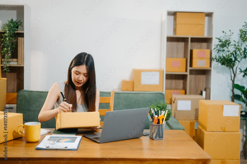 Young business owner woman prepare parcel box and standing check online orders for deliver Young business owner woman prepare parcel box and standing check online orders for deliver