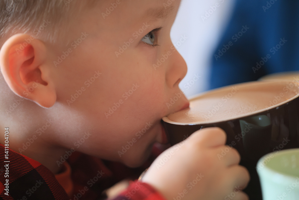 a boy drinking cocoa, a close-up of a five-year-old child and a cup of hot drink a boy drinking cocoa, a close-up of a five-year-old child and a cup of hot drink