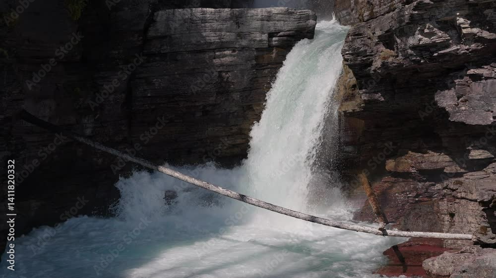Water rushes down St. Mary Falls, framed by rugged cliffs in Montana, USA