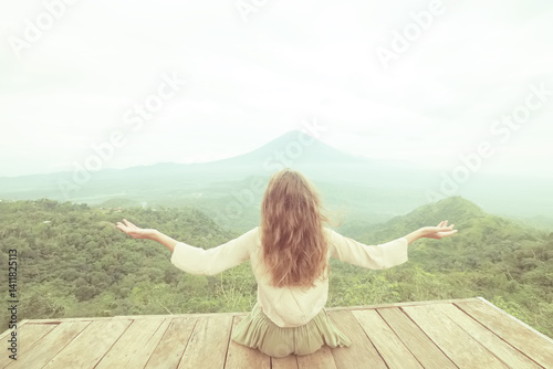 A girl meditates in the mountains view from the back, the height of Bali Agung mountain