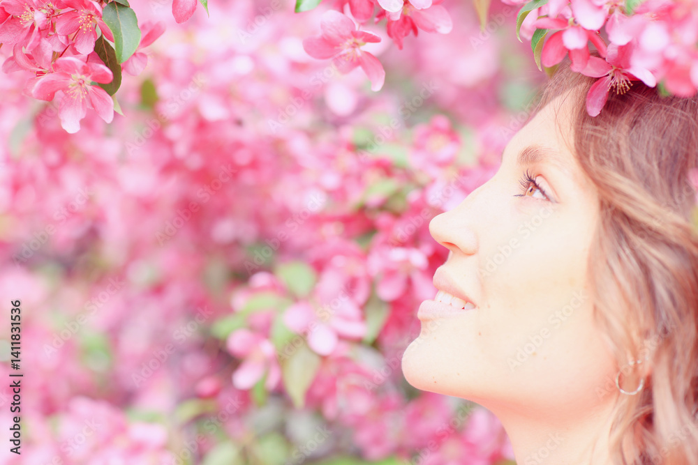 Fototapeta premium Springtime background, a woman in pink in a blooming cherry orchard, a model posing in a romantic style