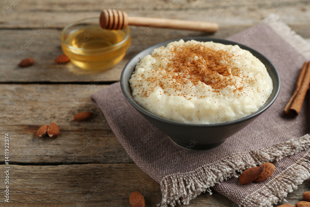 Delicious rice pudding with cinnamon, honey and almonds on wooden table, closeup Delicious rice pudding with cinnamon, honey and almonds on wooden table, closeup