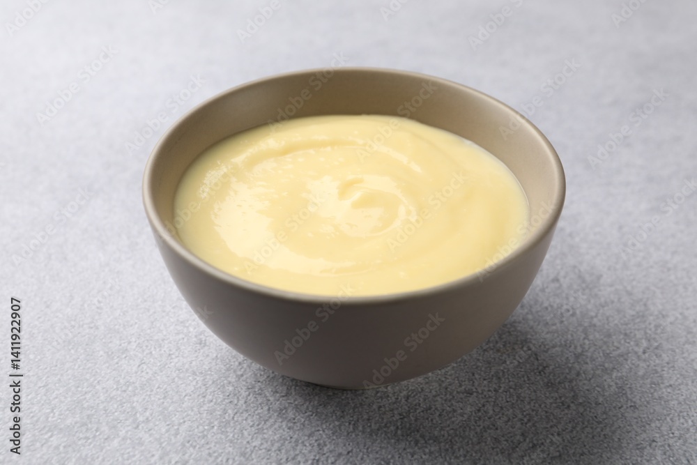 Tasty vanilla pudding in bowl on light grey table, closeup Tasty vanilla pudding in bowl on light grey table, closeup