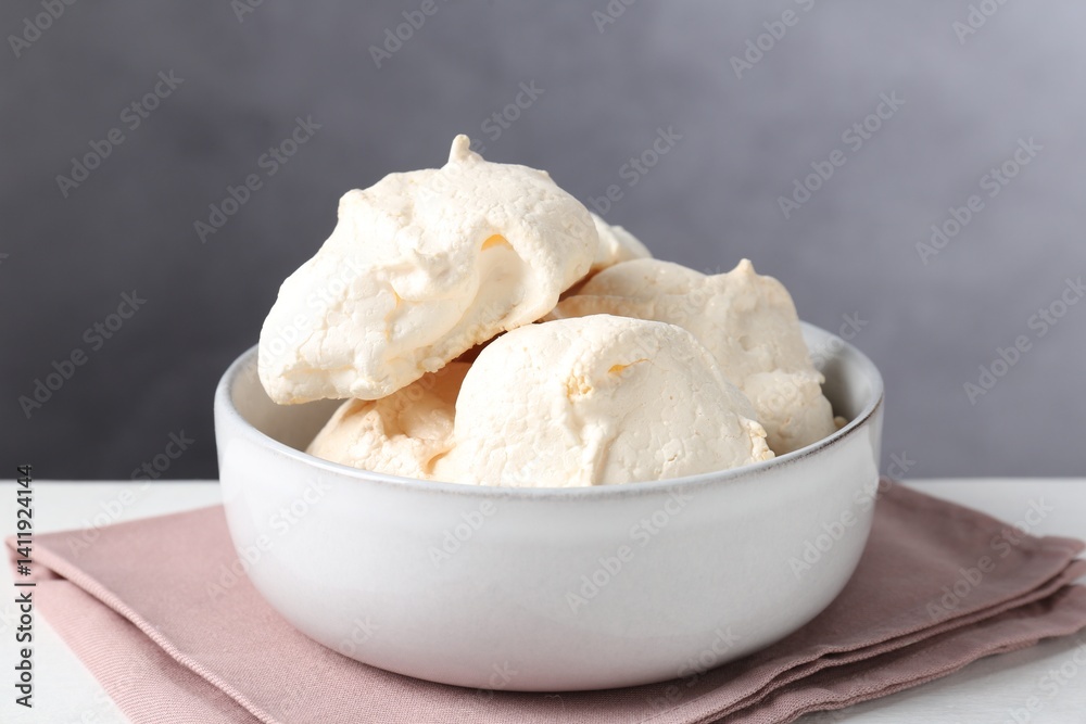 Delicious homemade meringue cookies in bowl on light table against gray background, closeup Delicious homemade meringue cookies in bowl on light table against gray background, closeup